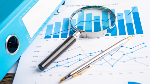 Photo of data graph and magnifying glass and pen