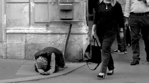 Image of wealthy white people walking past a black beggar