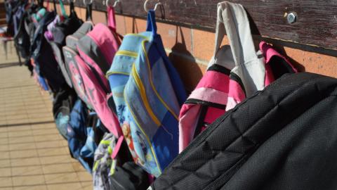 Photo of schoolbags hanging against a wall