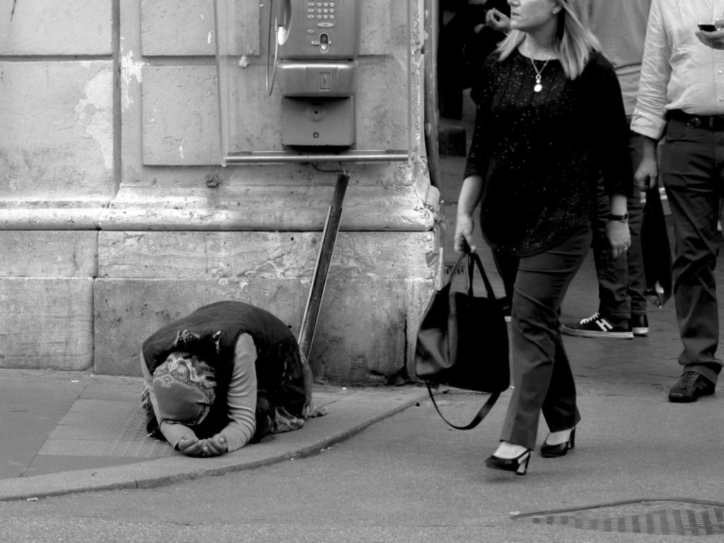 Image of wealthy white people walking past a black beggar