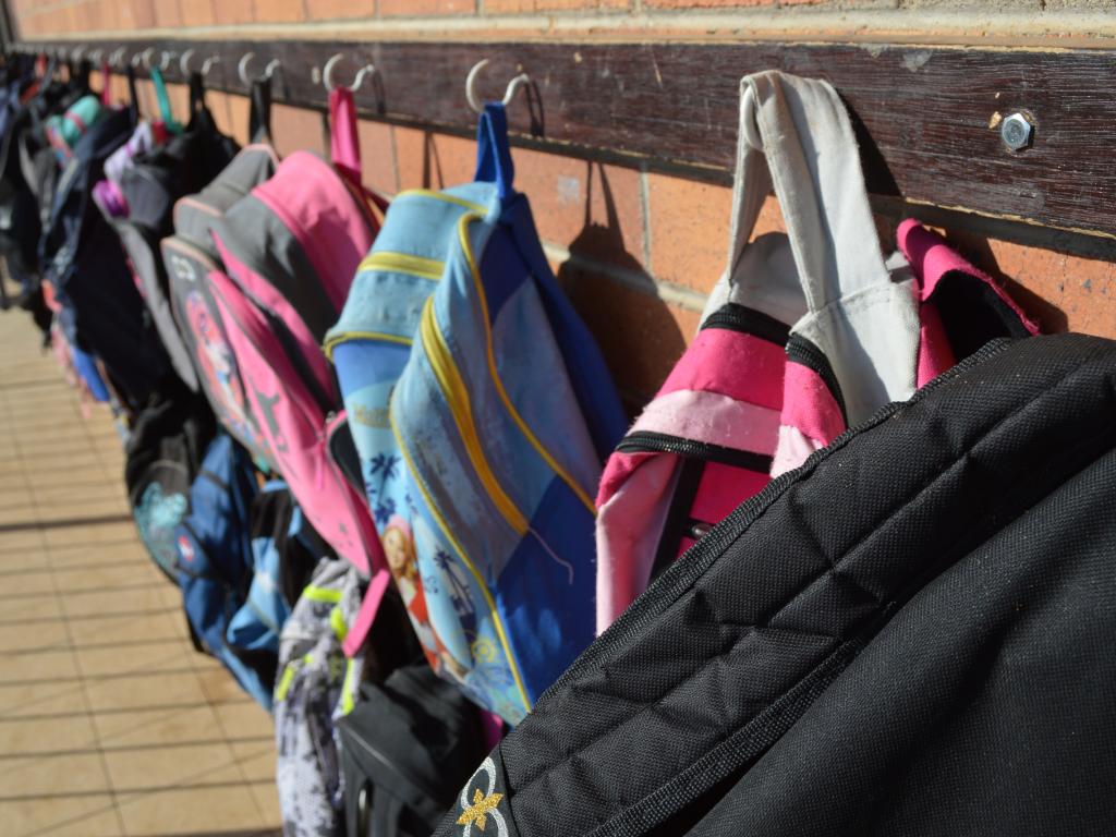 Photo of schoolbags hanging against a wall